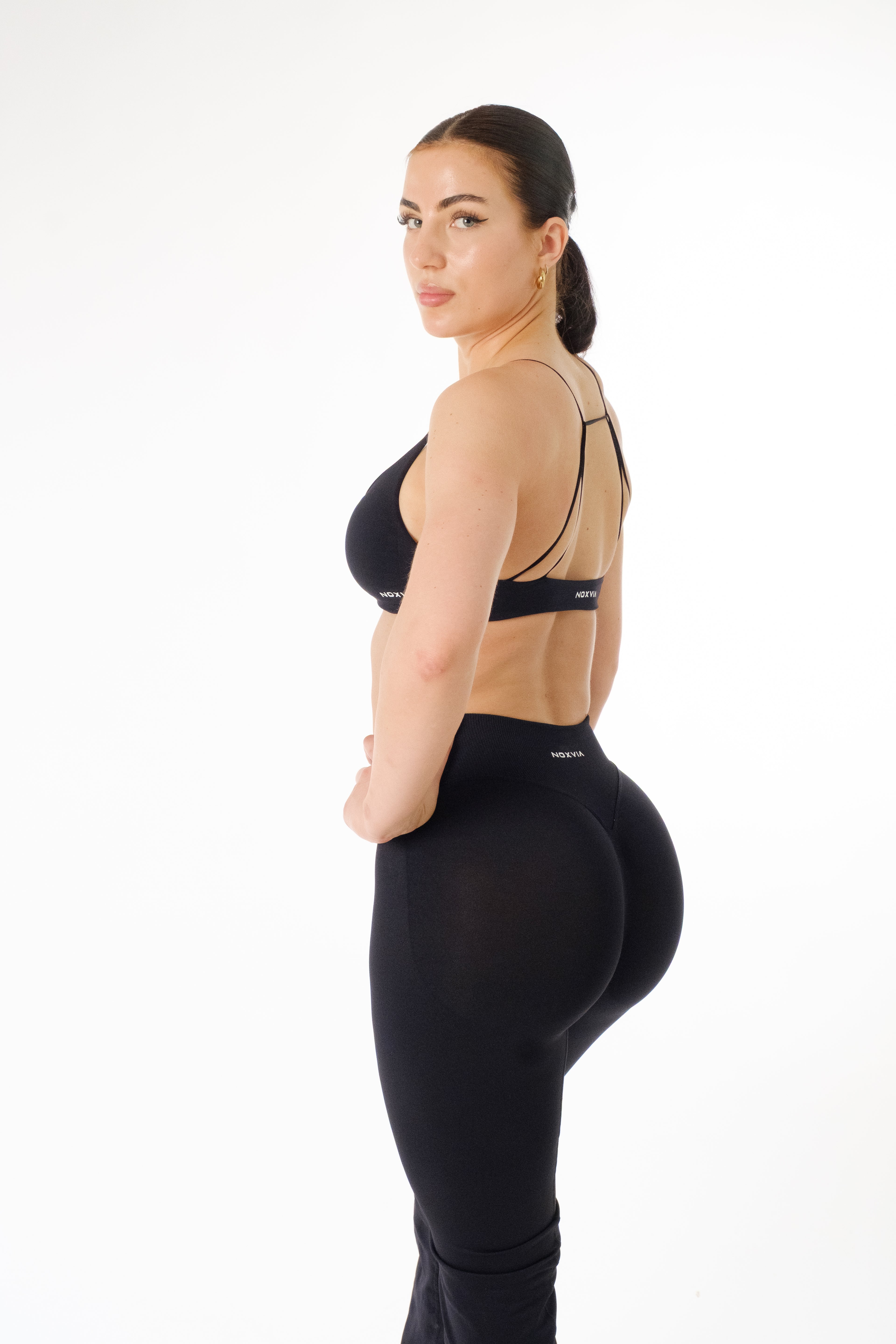 Side and back view of NOXVIA IMPERIUM black high-waisted sculpt leggings with matching strappy sports bra