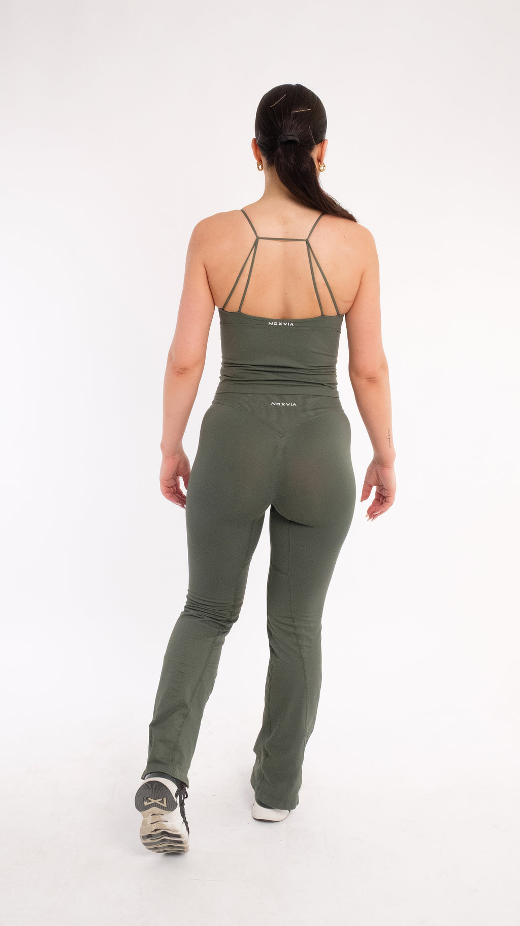 Back view of NOXVIA NOVA Olive high-waisted flare leggings showing rear contour shaping with matching strappy training top