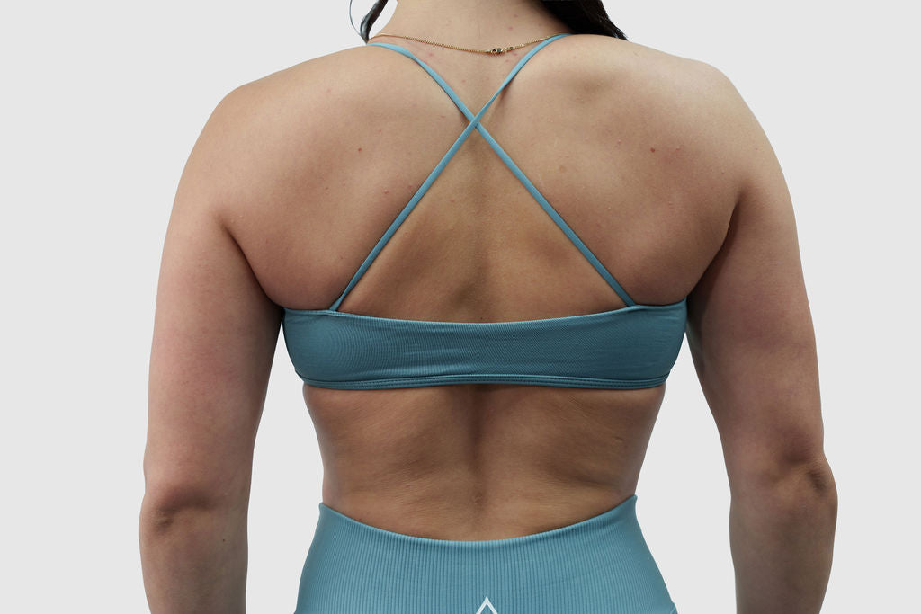 NOXVIA Shadow Olive sports bra, back detail showing the cross-back straps, open-back design and supportive underband
